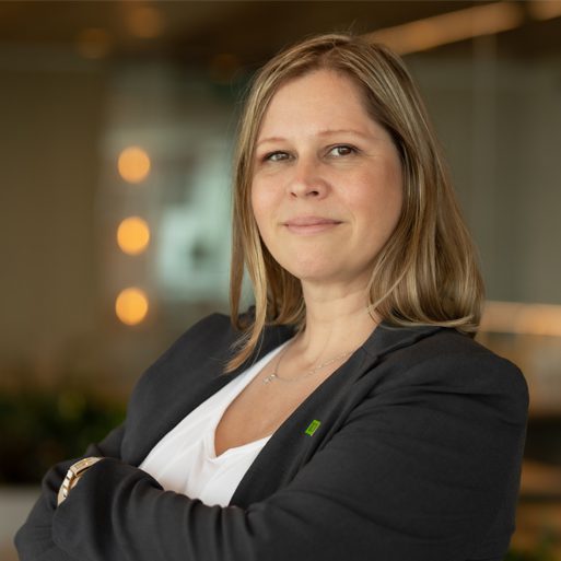 Une collègue en habit sourit les bras croisés dans une salle de conférence.
