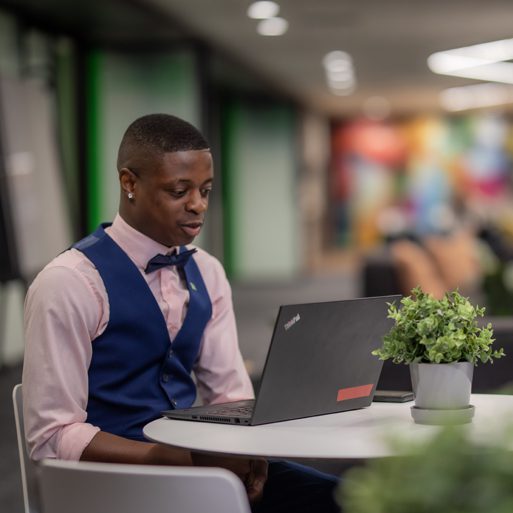 TD insurance Une enfant est assise sur les épaules de son père, qui travaille sur son ordinateur portable dans la cuisine.