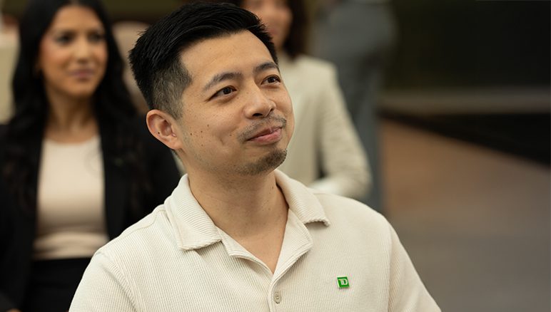 Homepage image 2 A new colleague smiles in front of a whiteboard inside a TD office.