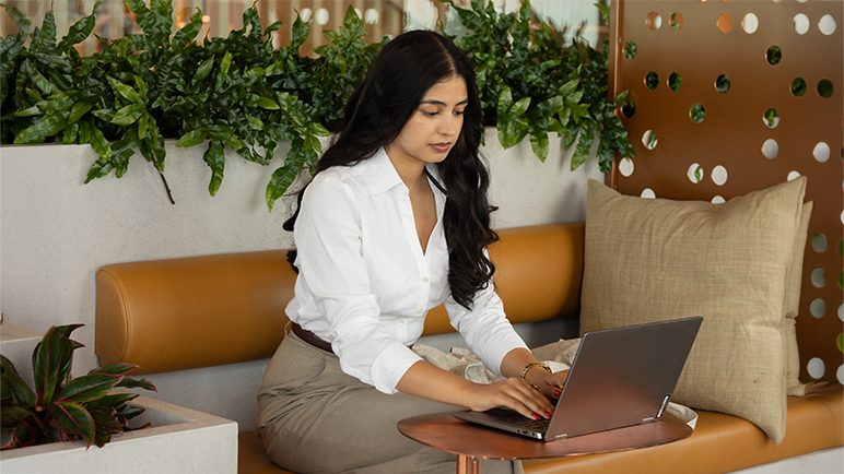 A job candidate smiles while seated in front of a laptop at home.