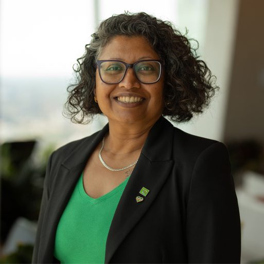 Une collègue portant un hijab et une épinglette verte de la TD sourit dans un bureau.