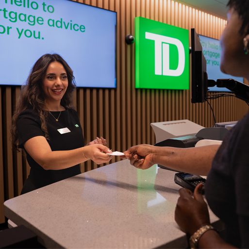 personal banking A couple smile while seated together on a couch looking at a laptop.