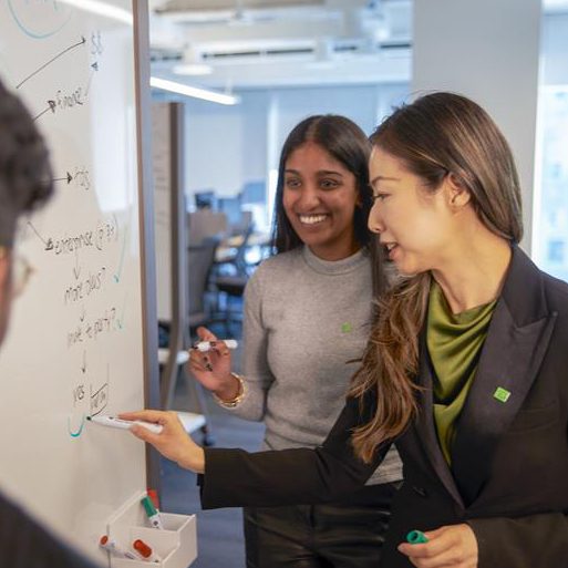 Un collègue assis devant un terminal d’ordinateur chargé lit un courriel sur son téléphone.