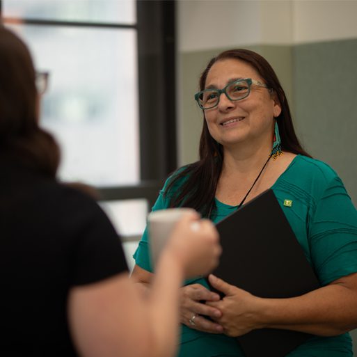 Deux collègues discutent à côté d’une grande fenêtre dans un bureau de la TD.