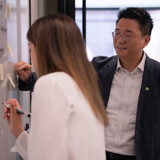 Une collègue présente un travail sur son ordinateur portable en souriant.