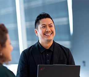 Two colleagues talk business while looking at a laptop in an office.