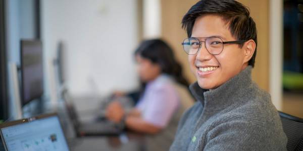 A new colleague smiles while working in an open concept office.