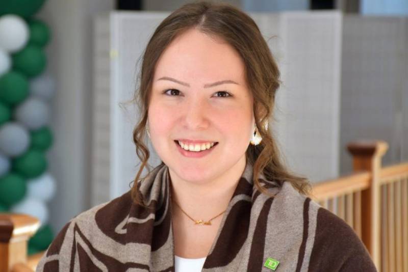 A colleague wearing a green TD pin smiles while at work.