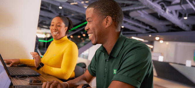A colleague shares insights with an intern while sitting at a desk together.