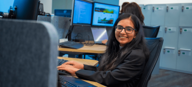 An intern smiles while working on a laptop.