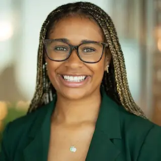 A colleague with a green TD lapel pin smiles at the camera in a TD office.